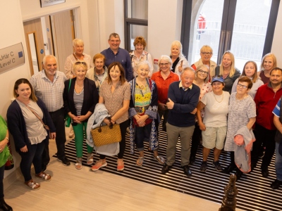A large group of people standing inside the front door of a healthcare facility.