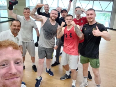 Nine men in a gymnasium wearing sports clothing.