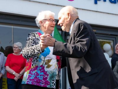 An older couple dancing together with other people standing around them.