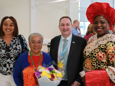 Dame Elizabeth Anionwu holding a bouquet of flowers and standing with a man and two other women.