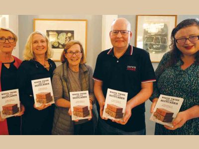 Five people standing indoors, each holding a book titled ‘White Twine and Old Suitcases’.