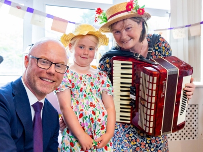 Minister Stephen Donnelly with a child and a woman holding an accordion musical instrument.