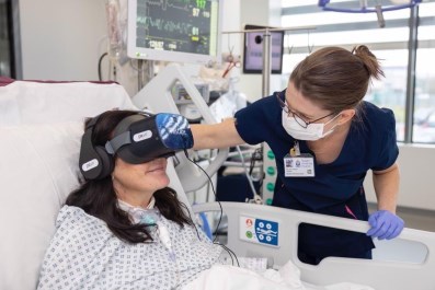 Dr Melanie Ryberg is at a female patient's bedside - the patient is wearing headphones and an is using visual technology equipment