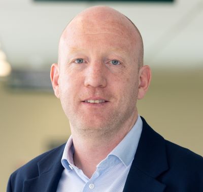 Headshot of Fintan O’Hara looking straight ahead. Fintan is waering a blue shirt and a navy jacket. 