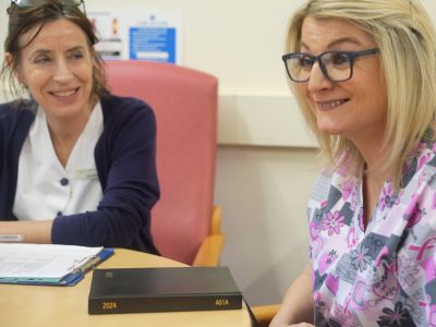 2 women sitting at a table in a healthcare setting.