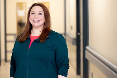 Sarah Williams stands in a hospital corridor smiling directly ahead