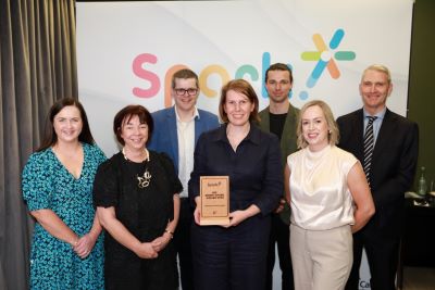 Group of people standing in front of the Spark logo. A lady in the front is holding a HSE Spark front plaque. 