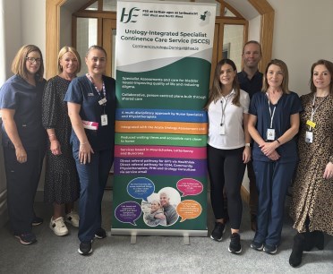 Group of healthcare professionals in uniforms standing beside a pull up information stand