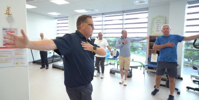 Group of men in a gym setting doing arm stretching exercises