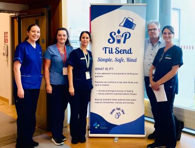 5 healthcare workers standing beside a pull up stand. The pull stands reads: Sip till send, Simple Safe, Kind. 