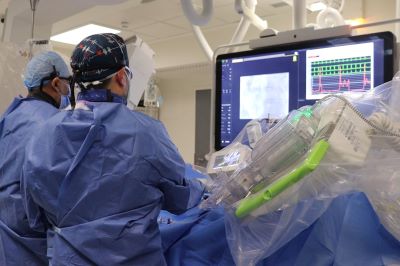 Two healthcare professionals working on a patient by using a large screen.