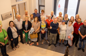 A large group of people standing inside the front door of a healthcare facility.