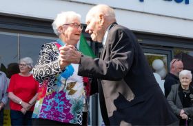 An older couple dancing together with other people standing around them.