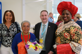 Dame Elizabeth Anionwu holding a bouquet of flowers and standing with a man and two other women.