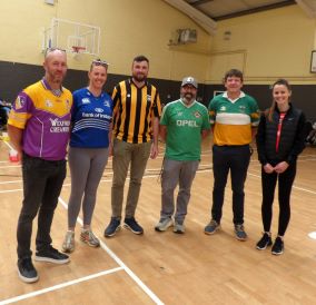 Group of 6 people, 2 women and 4 men. They are wearing sports clothes and are in a sports hall.