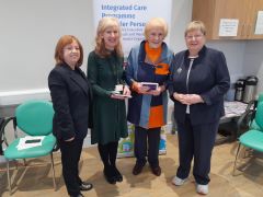 Pictured at the launch of Older people live well at home in Laois Offaly is Anna May McHugh, Managing Director of the National Ploughing Association. She is joined by 3 ladies, each are standing in front of a pull-up banner that reads: Integrated Care Programme Older Persons. 