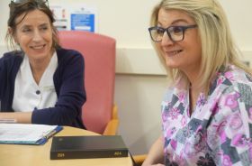 2 women sitting at a table in a healthcare setting.
