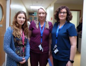 Three female healthcare workers standing in a health service corridor. 