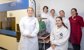 Group of lab healthcare staff standing around a computer. 