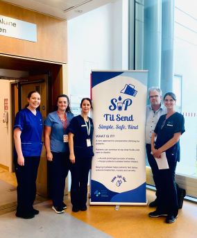 5 healthcare workers standing beside a pull pull stand. The pull up stand reads: Sip till send. Simple, Safe, kind. 