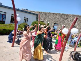 Women in colourful traditional dress dancing in an outdoor courtyard